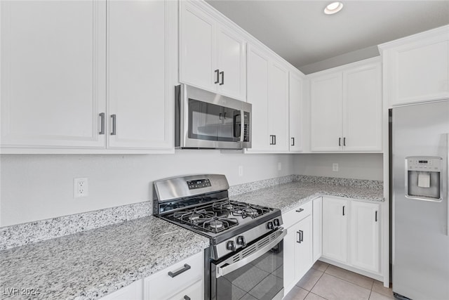 kitchen with light tile patterned floors, light stone counters, white cabinetry, and appliances with stainless steel finishes