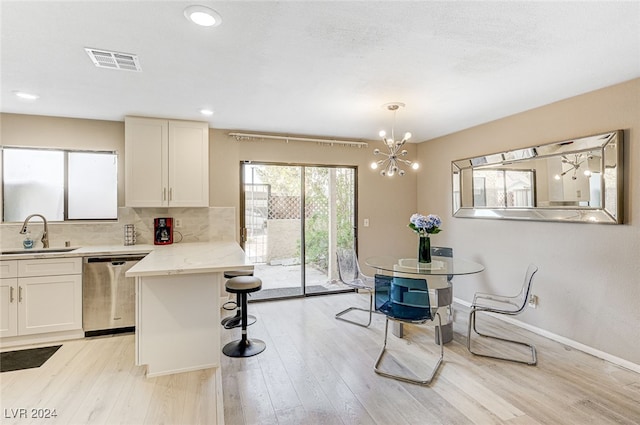 kitchen featuring backsplash, sink, pendant lighting, light hardwood / wood-style flooring, and dishwasher