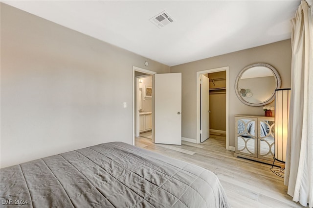 unfurnished bedroom with a spacious closet, light hardwood / wood-style flooring, and a closet