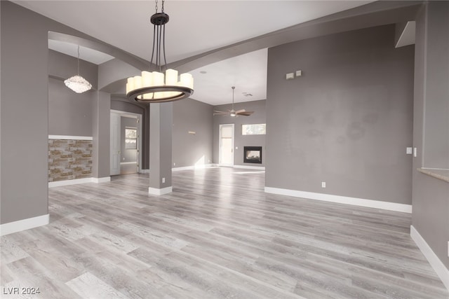 unfurnished living room featuring light hardwood / wood-style flooring and ceiling fan with notable chandelier