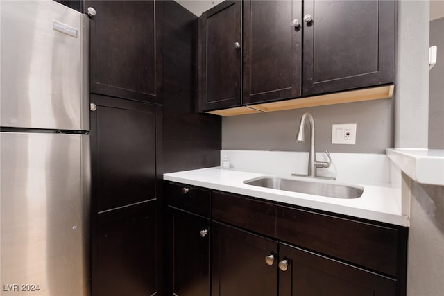 kitchen with dark brown cabinetry, stainless steel fridge, and sink