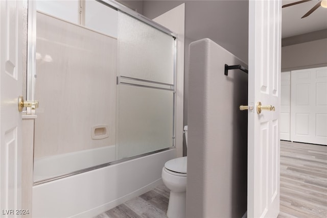 bathroom featuring enclosed tub / shower combo, ceiling fan, wood-type flooring, and toilet