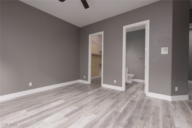 unfurnished bedroom with a walk in closet, ensuite bath, ceiling fan, light hardwood / wood-style floors, and a closet