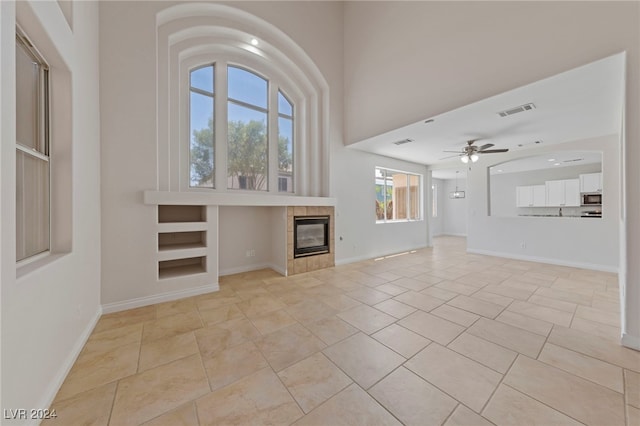 unfurnished living room featuring light tile patterned floors, a wealth of natural light, and ceiling fan