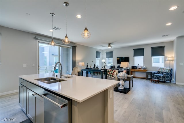 kitchen with pendant lighting, dishwasher, sink, light wood-type flooring, and an island with sink