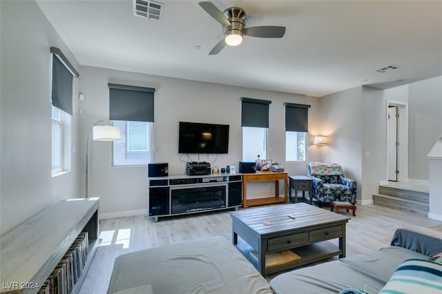 living room featuring light hardwood / wood-style floors, ceiling fan, and a healthy amount of sunlight