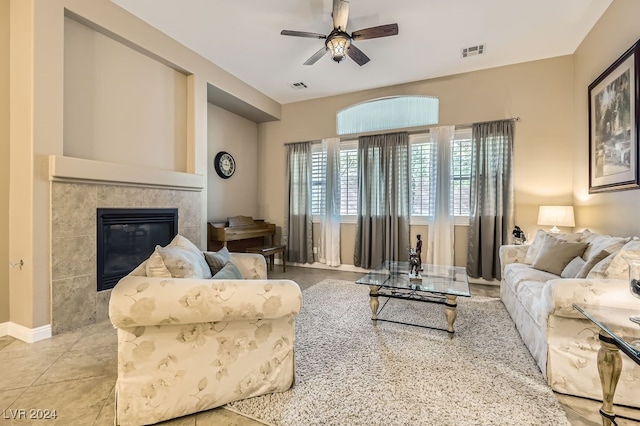 living room with a tile fireplace, ceiling fan, and light tile patterned floors