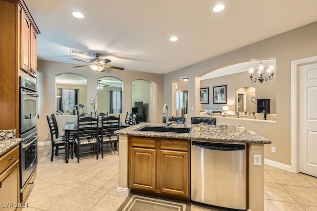 kitchen featuring a center island with sink, ceiling fan with notable chandelier, sink, light tile patterned floors, and appliances with stainless steel finishes