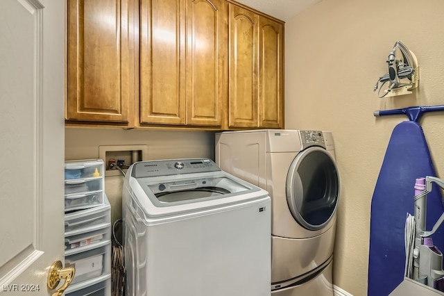 clothes washing area featuring washer and clothes dryer and cabinets