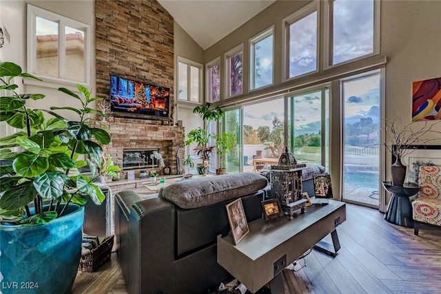 living room featuring a stone fireplace, wood-type flooring, and high vaulted ceiling