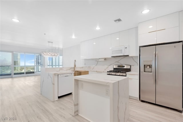 kitchen with appliances with stainless steel finishes, light hardwood / wood-style flooring, pendant lighting, and sink