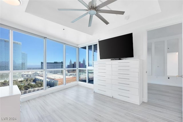 4575 Dean Martin Dr Unit 2211, Las Vegas, NV 89103 - unfurnished bedroom with light wood-style flooring, multiple windows, a ceiling fan, and a tray ceiling