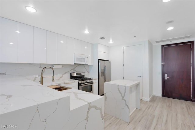 4575 Dean Martin Dr Unit 2211, Las Vegas, NV 89103 - kitchen with stainless steel appliances, modern cabinets, white cabinets, light wood-style floors, and a kitchen island