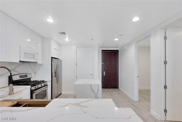 4575 Dean Martin Dr Unit 2211, Las Vegas, NV 89103 - kitchen featuring appliances with stainless steel finishes, white cabinetry, light wood-type flooring, light stone counters, and recessed lighting
