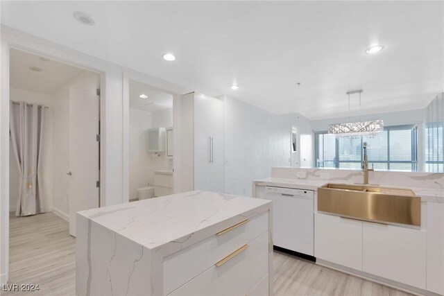 4575 Dean Martin Dr Unit 2211, Las Vegas, NV 89103 - kitchen featuring dishwasher, a sink, light wood-style floors, a center island, and white cabinetry