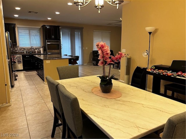 tiled dining area featuring ceiling fan with notable chandelier and sink