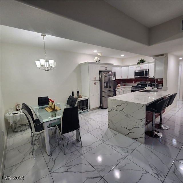 kitchen with light stone countertops, stainless steel appliances, sink, decorative light fixtures, and white cabinets