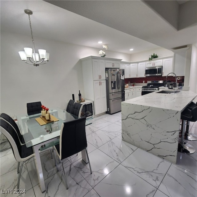 kitchen with sink, stainless steel appliances, pendant lighting, decorative backsplash, and white cabinets