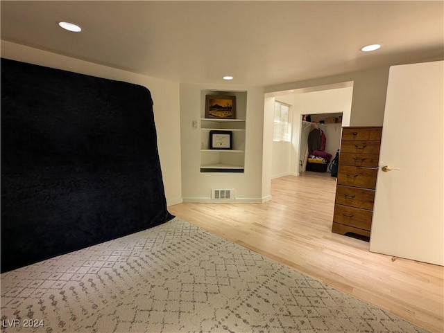 empty room featuring baseboards, built in features, recessed lighting, light wood-style flooring, and visible vents