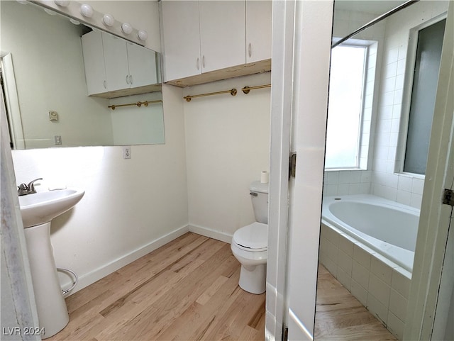 bathroom featuring sink, toilet, a relaxing tiled tub, and hardwood / wood-style flooring