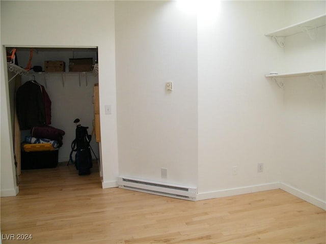 laundry room featuring baseboard heating and light hardwood / wood-style flooring