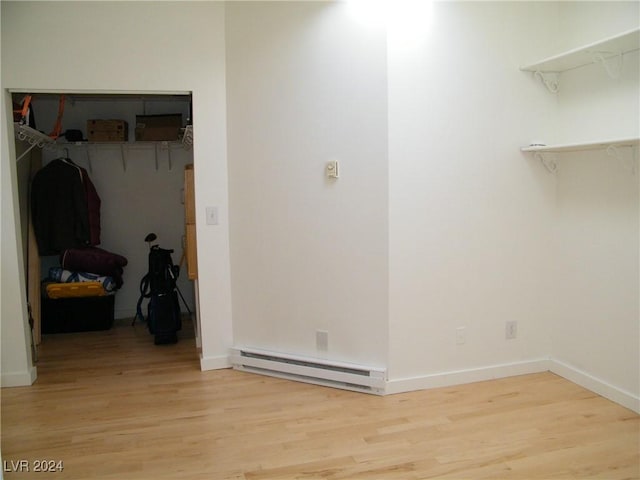 interior space with baseboard heating, baseboards, and light wood-style flooring