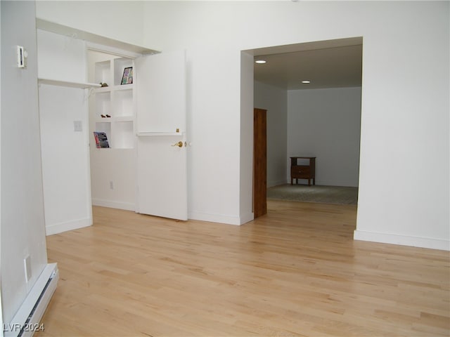 unfurnished room with light wood-type flooring and a baseboard heating unit