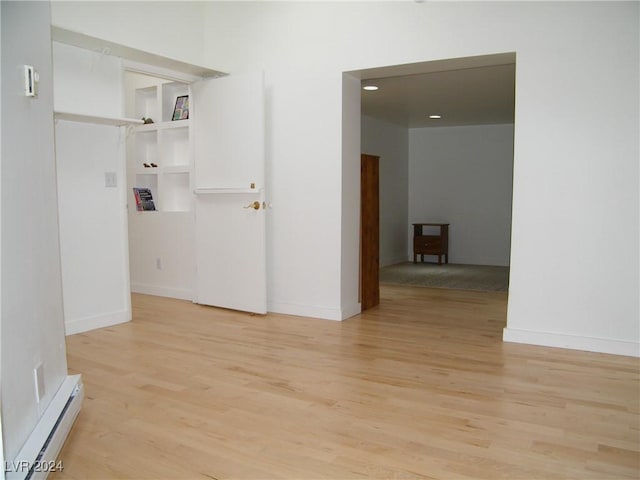 empty room with a baseboard radiator and light hardwood / wood-style floors