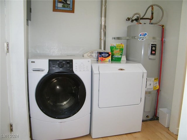 washroom with light hardwood / wood-style flooring, secured water heater, and washer and clothes dryer