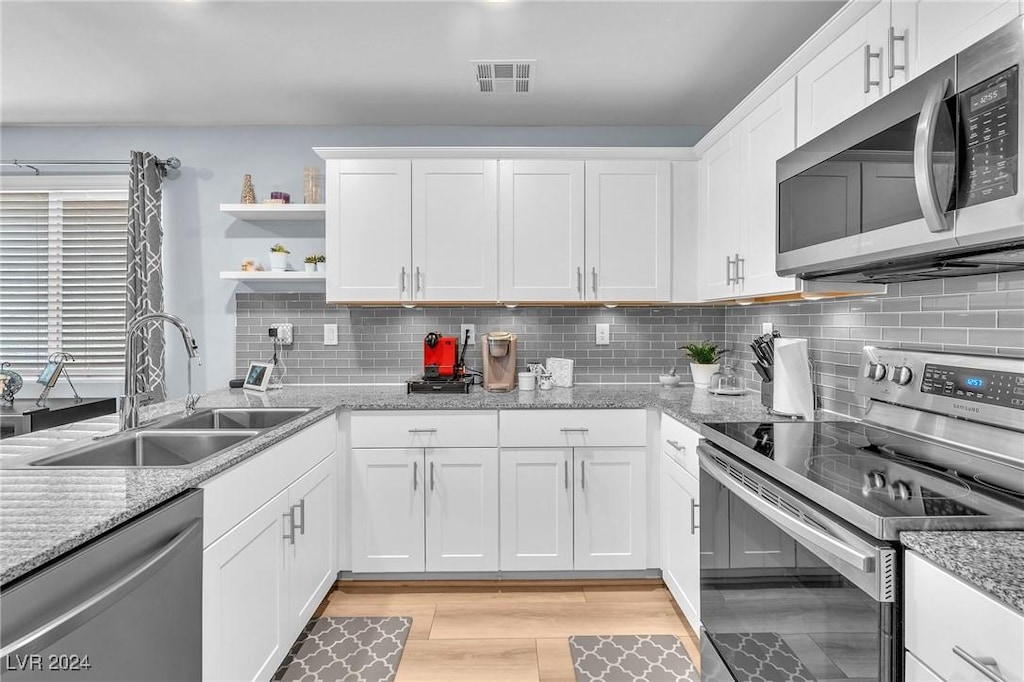 kitchen featuring light stone countertops, white cabinetry, sink, and appliances with stainless steel finishes