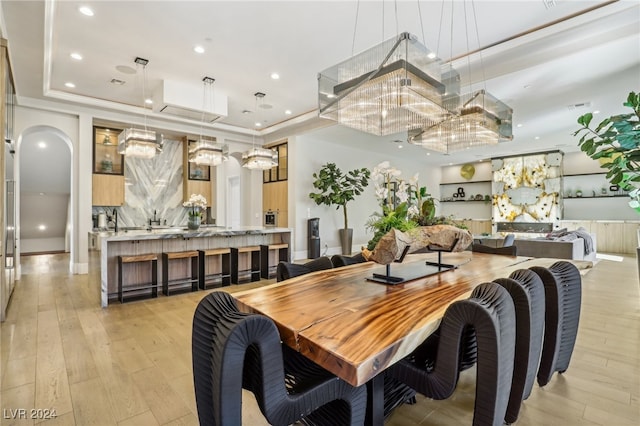 dining room featuring a raised ceiling and light hardwood / wood-style floors