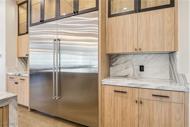 kitchen featuring light stone countertops, light hardwood / wood-style flooring, light brown cabinetry, and built in refrigerator