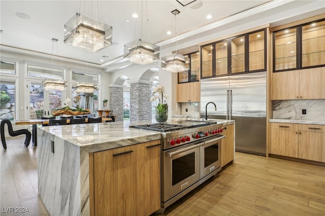 kitchen featuring pendant lighting, premium appliances, and a healthy amount of sunlight