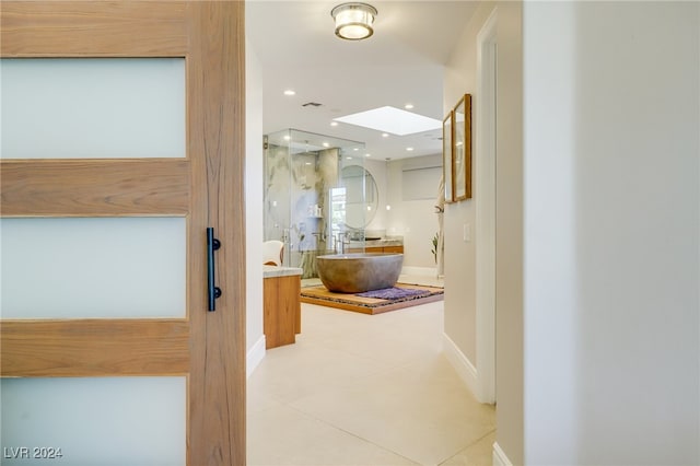 corridor with a skylight and light tile patterned flooring