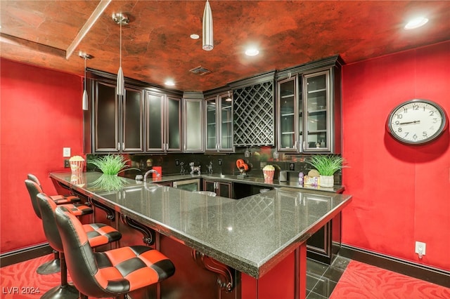 kitchen featuring pendant lighting, backsplash, a kitchen breakfast bar, dark stone countertops, and kitchen peninsula