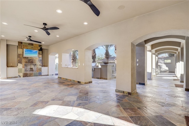 interior space with ceiling fan and an outdoor stone fireplace