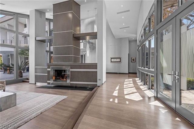 unfurnished living room featuring french doors, expansive windows, wood-type flooring, and a high ceiling