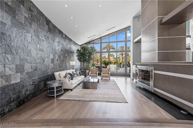 unfurnished living room featuring hardwood / wood-style flooring, high vaulted ceiling, and a wall of windows