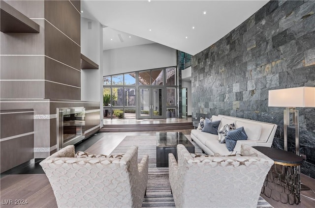 living room featuring dark wood-type flooring, a high ceiling, and tile walls