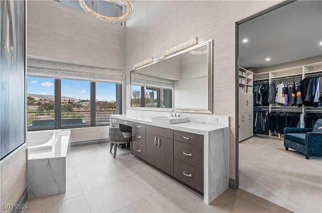 bathroom featuring a chandelier, vanity, tile patterned floors, and a bathtub