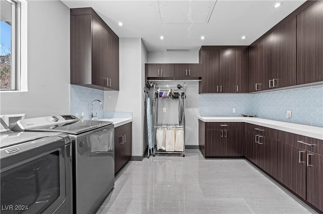 clothes washing area with washer and clothes dryer, cabinets, and sink