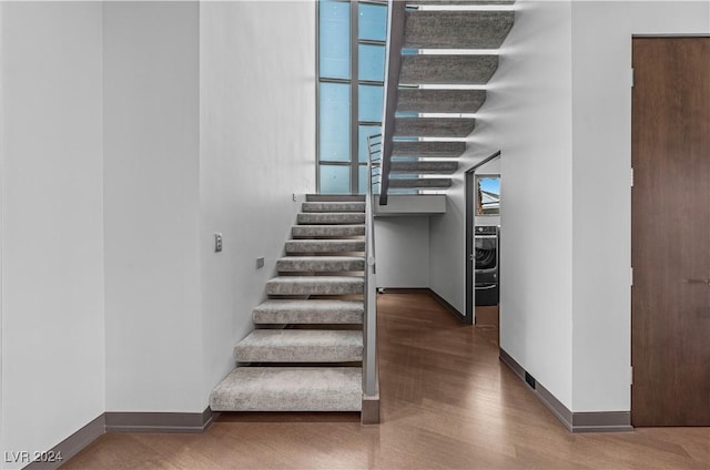 stairway with wood-type flooring and washer / clothes dryer