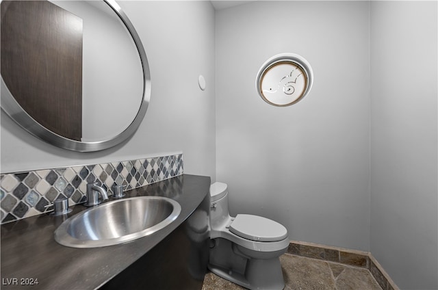 bathroom with toilet, sink, and tasteful backsplash