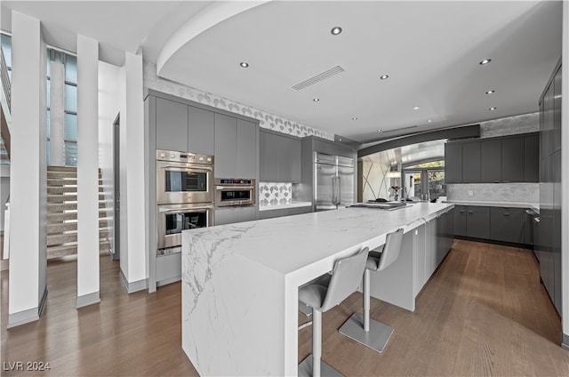 kitchen featuring a large island, gray cabinets, dark hardwood / wood-style flooring, and appliances with stainless steel finishes