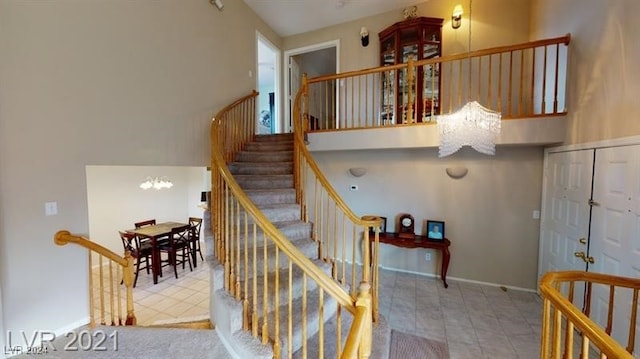 stairs with a towering ceiling and a chandelier