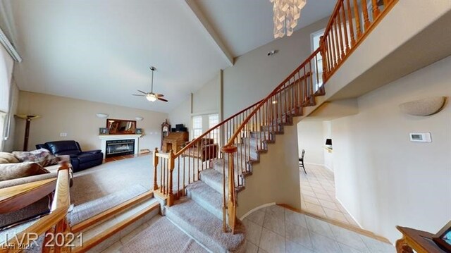 staircase featuring tile patterned flooring, ceiling fan, and high vaulted ceiling