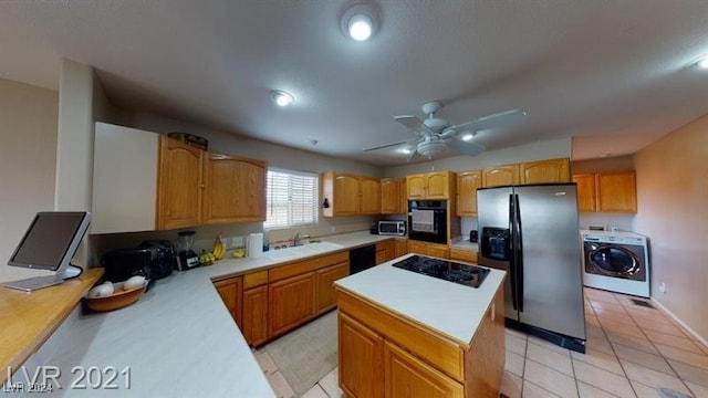 kitchen with washer / dryer, sink, a center island, light tile patterned floors, and black appliances