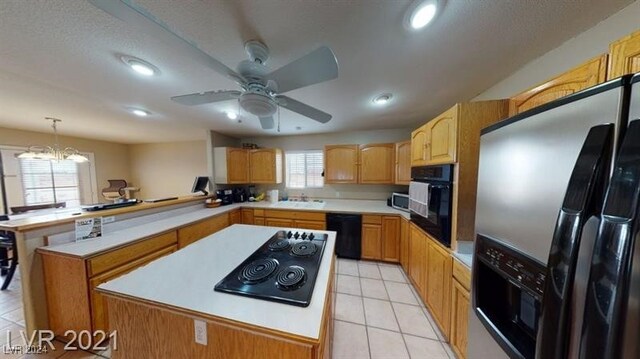 kitchen with sink, a center island, hanging light fixtures, light tile patterned floors, and black appliances