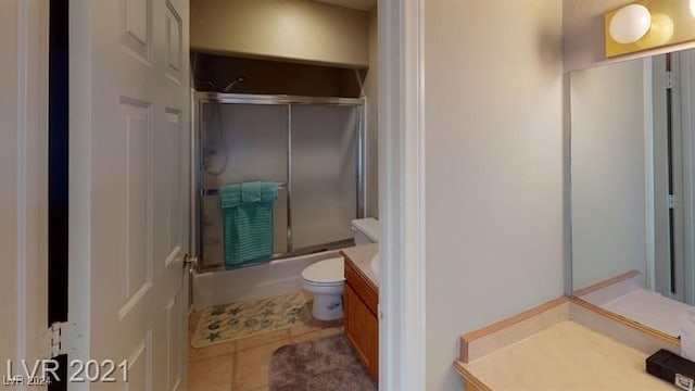 full bathroom featuring vanity, tile patterned flooring, shower / bath combination with glass door, and toilet