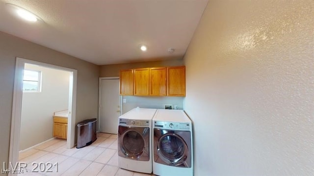 washroom featuring cabinets, light tile patterned floors, and washer and clothes dryer